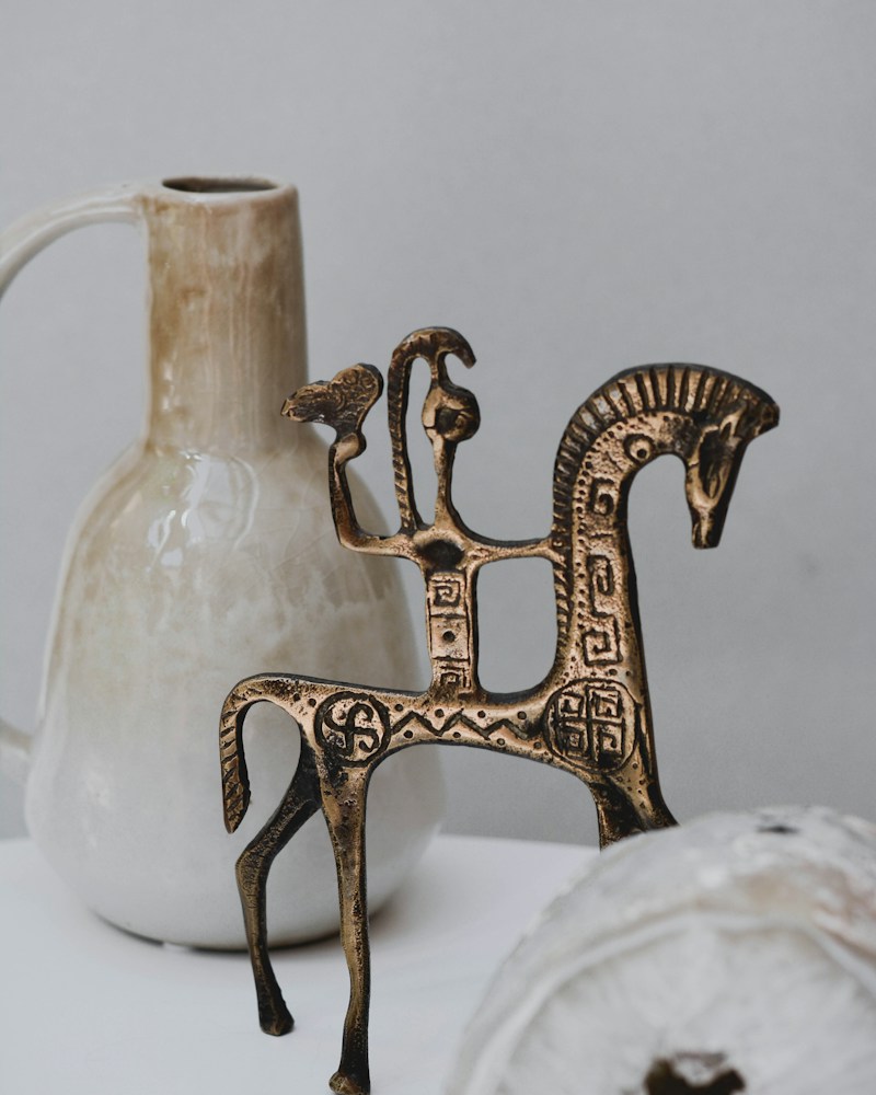Gold metal deer figurine on a white textile surface