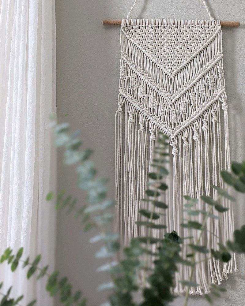 Textile wall hanging styled with indoor plants against a white wall